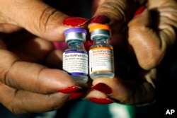 FILE - A nurse holds a vial of the Pfizer COVID-19 vaccine for children ages 5 to 11, right, and a vial of the vaccine for adults, which has a different colored label, at a vaccination station in Jackson, Miss., Feb. 8, 2022.