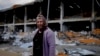 Жінка стоїть перед будинком, пошкодженим нападами в Ірпіні, на околиці Києва, Україна, 26 травня 2022 року.