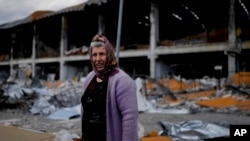 A woman stands in front of a building damaged by attacks in Irpin, on the outskirts Kyiv, Ukraine, May 26, 2022.