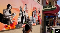 Two women walk along Jackson Street in Chinatown past the new 'AAPI Community Heroes' mural in San Francisco, May 23, 2022.