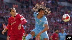 Nathan Ake dari Manchester City melompat untuk mengejar bola di sebelah Virgil van Dijk dari Liverpool, kiri, di stadion Wembley di London, Sabtu, 16 April 2022. (Foto: AP)