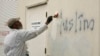 FILE - Seorang pria melukis di atas grafiti rasis di sisi masjid yang oleh para pejabat disebut sebagai kejahatan rasial, di Roseville, California, 1 Februari 2017.
