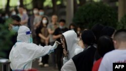Seorang petugas kesehatan mengambil sampel swab dari seorang perempuan untuk diuji COVID-19 di tempat pengambilan swab di Beijing, 27 Mei 2022. (Foto: AFP)