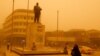 A woman walks past a statue of Iraqi poet Abdel Ghani Maarouf al Rusafi during a sandstorm in Baghdad, Iraq, May 16, 2022.