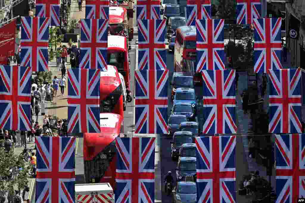 Red London buses and taxis pass beneath Union flags, put up to celebrate Queen Elizabeth's Platinum Jubilee, in Regent Street in central London.