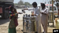 Relawan membagikan air kepada masyarakat di pinggir jalan pada musim panas di Karachi pada 14 Mei 2022. (Foto: AFP)