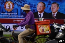 FILE - A cyclist rides past an electoral hoarding of Cambodia's Prime Minister and leader of the ruling Cambodian People's Party (CPP) Hun Sen, in Phnom Penh on July 26, 2018.