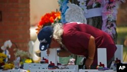 A man kisses the cross of Layla Salazar at a memorial outside Robb Elementary School to honor the victims killed in this week's school shooting in Uvalde, Texas, May 28, 2022.
