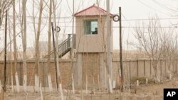 FILE - A security person watches from a guard tower around a detention facility in Yarkent County in northwestern China's Xinjiang Uyghur Autonomous Region on March 21, 2021.
