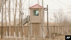 FILE - A security person watches from a guard tower around a detention facility in Yarkent County in northwestern China's Xinjiang Uyghur Autonomous Region, March 21, 2021.