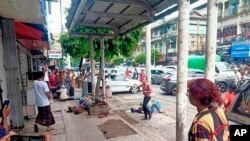In this photo provided by the information office of Myanmar's military, four injured people can be seen lying on the pavement after an explosion at a bus stop in downtown Yangon, Myanmar, May 31, 2022. 