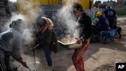 Women cook at a soup kitchen to feed residents in the Puerta de Hierro neighborhood, in La Matanza district of Buenos Aires, Argentina, May 11, 2022.