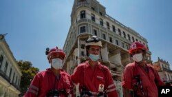 Trabajadores de la Cruz Roja Cubana se alejan del destruido Hotel Saratoga de cinco estrellas después de buscar entre los escombros tras una explosión mortal en La Habana Vieja, Cuba, el 10 de mayo de 2022.