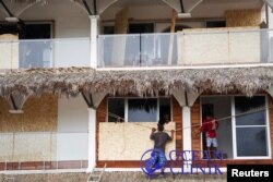 Men board up windows as they prepare for the arrival of Hurricane Agatha, in Puerto Escondido, Oaxaca state, Mexico, May 29, 2022.