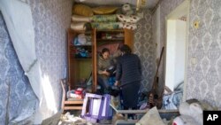 Women collect belongings in their apartment destroyed by Russian airstrike in Bakhmut, Donetsk region, Ukraine, May 7, 2022. 
