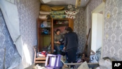 Qadınlar Ukraynanın Donetsk vilayətinin Baxmut şəhərində Rusiyanın hava hücumu nəticəsində dağıdılan mənzillərində əşyaları yığırlar, 7 may 2022-ci il.
