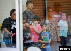 A child looks on through a glass window from inside the Ssgt Willie de Leon Civic Center, where students had been transported from Robb Elementary School after a shooting, in Uvalde, Texas, U.S. May 24, 2022. (REUTERS/Marco Bello)