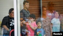 A child looks on through a glass window from inside the Ssgt Willie de Leon Civic Center, where students had been transported from Robb Elementary School after a shooting, in Uvalde, Texas, U.S. May 24, 2022. (REUTERS/Marco Bello)