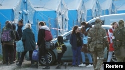 Civili evakuisani iz čeličane Azovstal hodaju u pratnji predstavnka Međunarodnog komiteta crvenog krsta i osoblja UN, uz prisustvo ruskih vojnika, u prihvatnom centru u selu Bezimene, tokom rata Rusije u Ukrajini, u regionu Donjetska, 6. maja 2022.