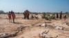 FILE - People stand next to the carcasses of dead sheep in the village of Hargududo, 80 kilometers from the city of Gode, Ethiopia, April 07, 2022. 