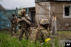 Ukrainian National Guard members patrol during a reconnaissance mission in a recently retaken village on the outskirts of Kharkiv, northeastern Ukraine, May 14, 2022.