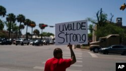 Alex Covarrubias, de 32 años, sostiene un cartel en la esquina de una calle para las víctimas del tiroteo del martes en la Escuela Primaria Robb en Uvalde, Texas, el 26 de mayo de 2022.