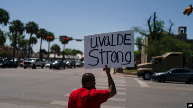 Alex Covarrubias, 32, holds up a sign at a street corner for the victims of Tuesday's shooting Robb Elementary School in Uvalde, Texas, May 26, 2022.