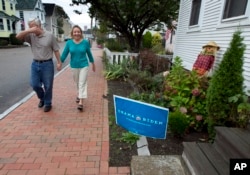 On Oct. 5, 2012, Joe Galli jokingly covers his face while walking by an Obama/Biden sign in front of a neighbor's home in Portsmouth, New Hampshire.