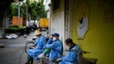 Workers in protective suits rest on a street during lockdown, amid the coronavirus disease (COVID-19) outbreak, in Shanghai, China, May 28, 2022.