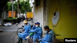 Workers in protective suits rest on a street during lockdown, amid the coronavirus disease (COVID-19) outbreak, in Shanghai, China, May 28, 2022.
