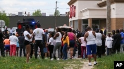 A crowd gathers as police investigate after a shooting at a supermarket, May 14, 2022, in Buffalo, N.Y.