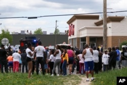 A crowd gathers as police investigate after a shooting at a supermarket, on May 14, 2022, in Buffalo, NY