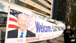 한 여성이 2022년 5월 21일 대한민국 서울 주재 미국대사관 근처에서 조 바이든 미국 대통령의 방문을 환영하는 표지판을 지나고 있다.