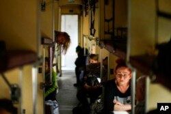 Orang-orang yang melarikan diri dari Lysychansk dan daerah lain duduk di kereta evakuasi di stasiun kereta api di Pokrovsk, Ukraina timur, Ukraina timur, 28 Mei 2022. (Foto: AP)