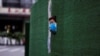 一位上海居民從封閉小區的圍欄空隙中伸出頭來張望。（2022年5月6日）