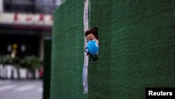 一位上海居民從封閉小區的圍欄空隙中伸出頭來張望。（2022年5月6日）