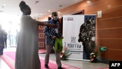 Une hôtesse dirige les visiteurs à l'entrée de la 14e édition de la Biennale d'art contemporain africain, le 19 mai 2022, au grand théâtre Doudou Ndiaye Coumba Rose.