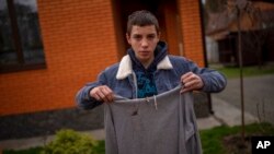 FILE - Yura Nechyporenko, 15, holds the hoodie he was wearing the day a Russian soldier tried to execute him in Bucha, on the outskirts of Kyiv, Ukraine, on April 19, 2022.