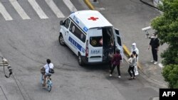 Residents are seen boarding an ambulance on a street next to a neigborhood during a Covid-19 coronavirus lockdown in the Jing'an district in Shanghai on May 8, 2022. (Photo by Hector RETAMAL / AFP)