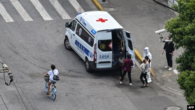 Residents are seen boarding an ambulance on a street next to a neigborhood during a Covid-19 coronavirus lockdown in the Jing'an district in Shanghai on May 8, 2022. (Photo by Hector RETAMAL / AFP)