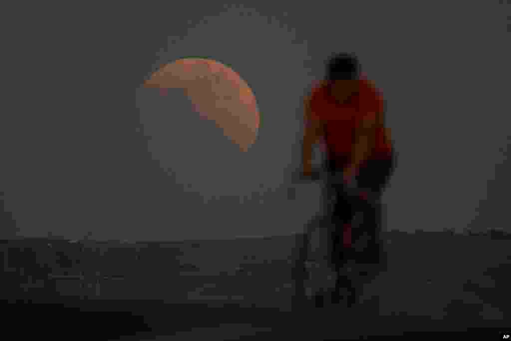 El eclipse lunar se ve detrás de un ciclista durante la primera luna de sangre del año, en Irwindale, California.