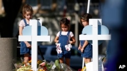 2022年5月26日，孩子们在德克萨斯州尤瓦尔迪一处悼念本周小学枪击案遇难者的纪念地表达敬意。（美联社）