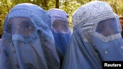 Mujeres afganas con burkas se detienen en una calle del este de Kabul mientras el grupo "La Coalición General de Mujeres" organizaba una reunión de mujeres afganas para manifestarse por sus derechos el 20 de noviembre de 2001.