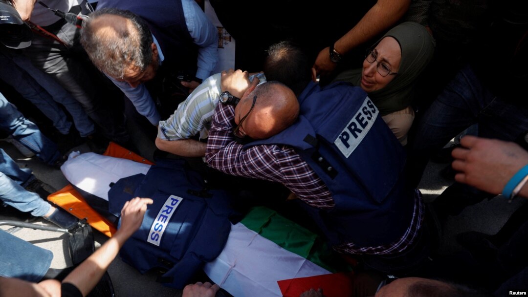 Mourners cluster near the body of Al Jazeera reporter Shireen Abu Akleh, who was shot and killed while covering an Israeli raid in the occupied West Bank town of Jenin on May 11, 2022, the Palestinian health ministry said.
