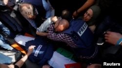 Mourners cluster near the body of Al Jazeera reporter Shireen Abu Akleh, who was shot and killed while covering an Israeli raid in the occupied West Bank town of Jenin on May 11, 2022, the Palestinian health ministry said.
