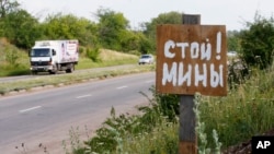 File - A poster reading 'Stop! Mines!' stands at a verge near the city of Kramatorsk, Donetsk region, eastern Ukraine. (AP Photo/Dmitry Lovetsky)