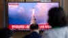 People watch a news program reporting about North Korea's missile launch with a file image, at a train station in Seoul, South Korea, May 25, 2022. Hours after U.S. President Joe Biden left Asia, North Korea launched three ballistic missiles toward the sea, its neighbors said.