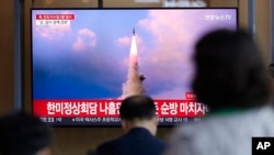 FILE - People watch a news program reporting about North Korea's missile launch showing a file image, at a train station in Seoul, South Korea, May 25, 2022.