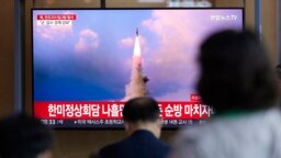 2022年5月25日，在韩国首尔的一个火车站，人们正在观看有关朝鲜导弹发射的新闻节目。