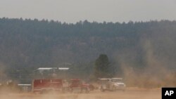 Wind kicks up dust at the fairgrounds as firefighters meet and confer about the wildfire raging on the other side of the hill behind them just outside of Las Vegas, NM, on May 7, 2022.